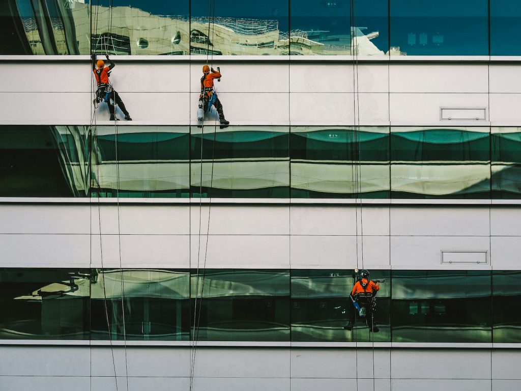 A technician washing the exterior of a white commercial building