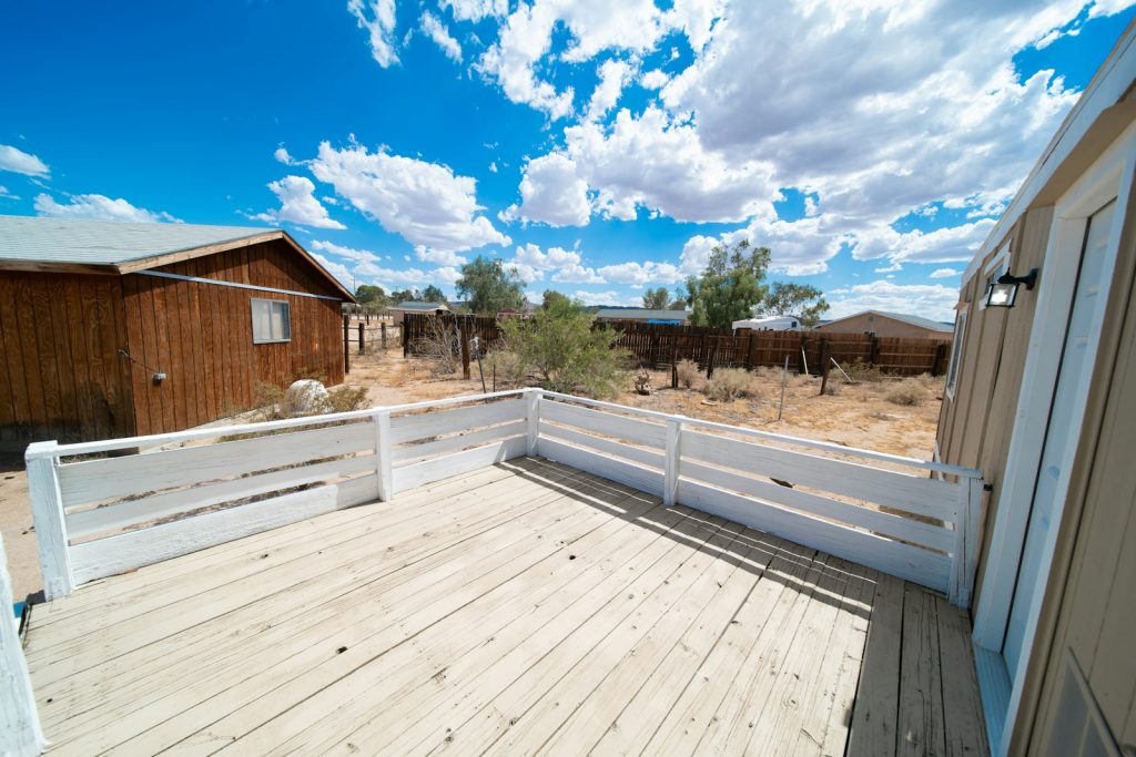 A wooden deck with a white fence beside a home after deck and fence cleaning
