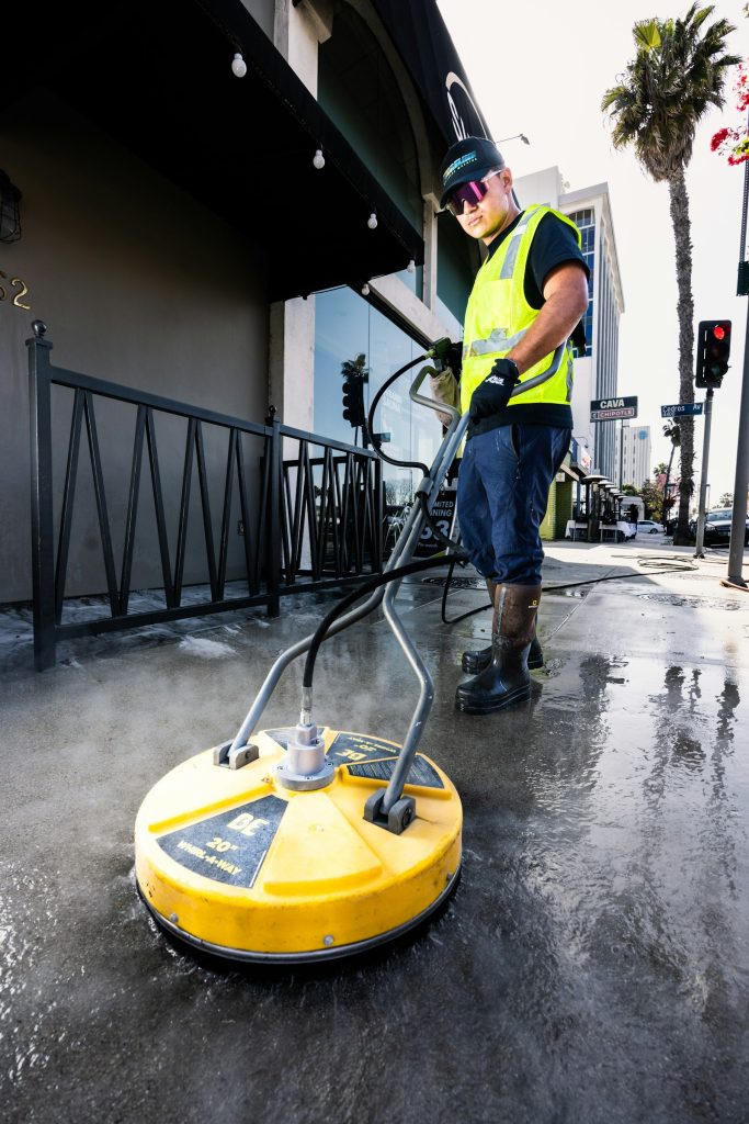 Crew member pressure washing a commercial hard surface area