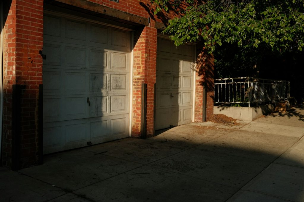 Sunlight across two clean white garage doors and a washed concrete apron