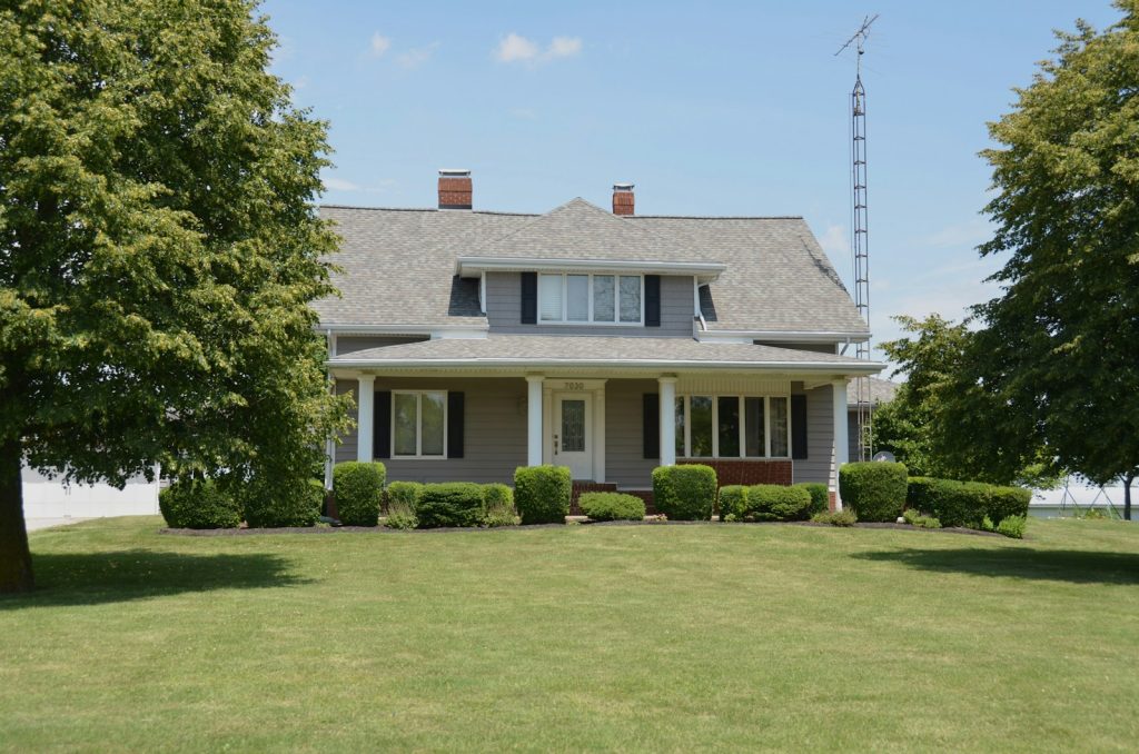 A traditional grey suburban house with a porch and green lawn in Fishers, Indiana